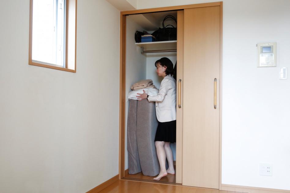 mujer guarda su ropa en armario casi vacio