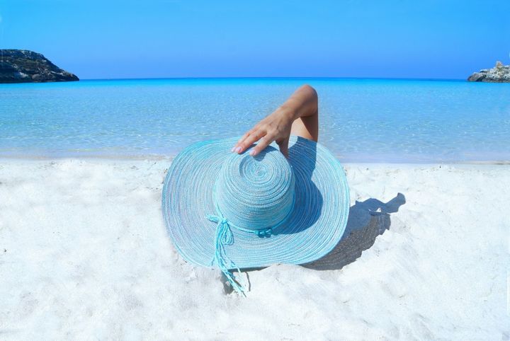 mujer sombrero descansando en la playa