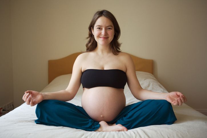 mujer embarazada meditando en la cama