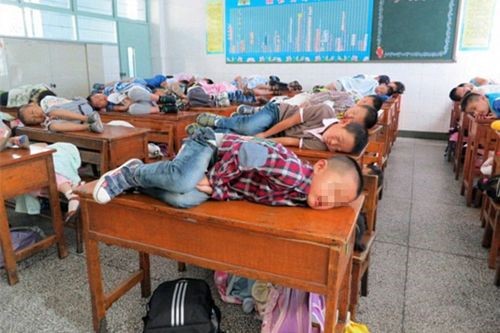 niños chinos dormidos en el salon de clases