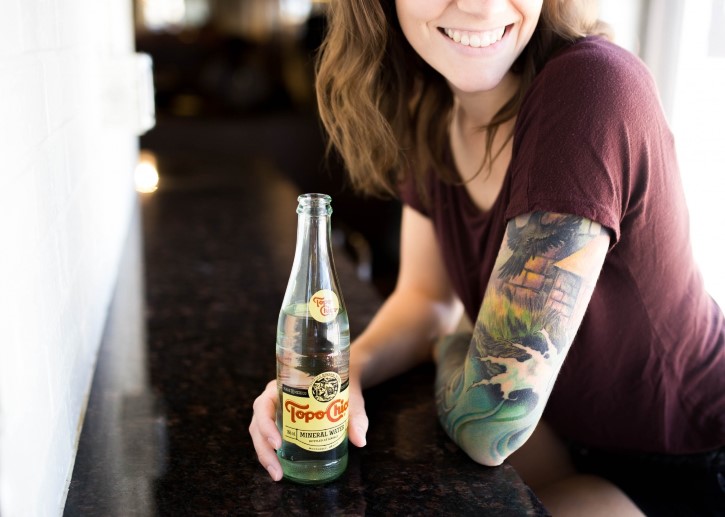 mujer tatuada bebiendo agua mineral