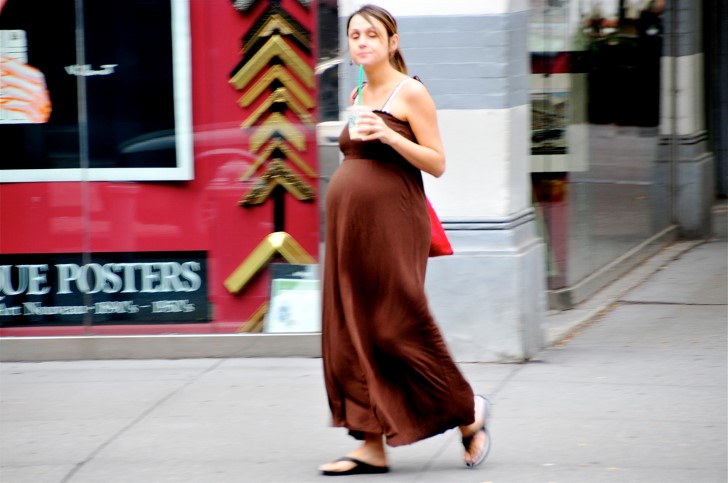 Mujer embarazada tomando cafe en la calle