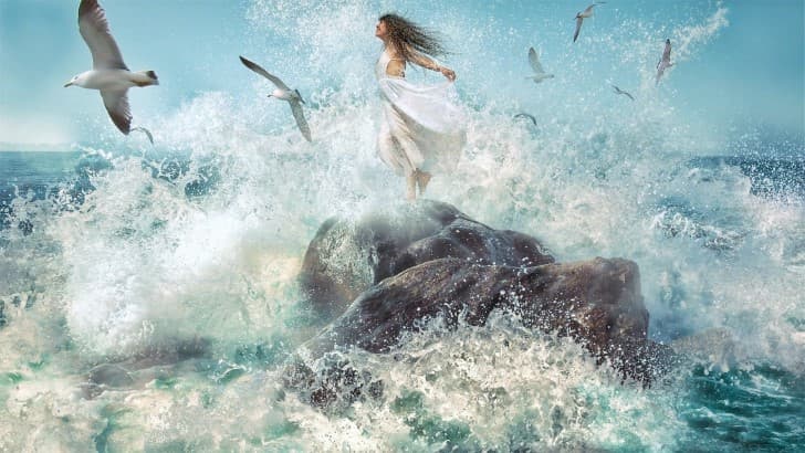 mujer sobre una roca en el oceano