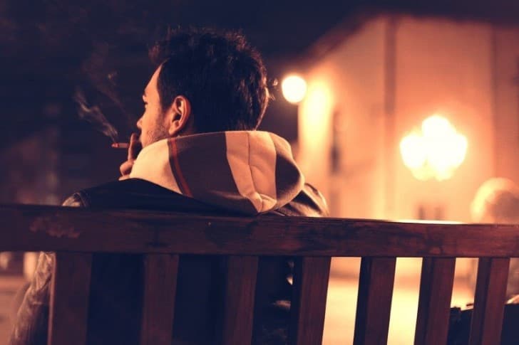 hombre sentado fumando un cigarrillo