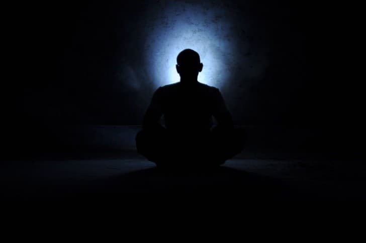 persona meditando en la oscuridad